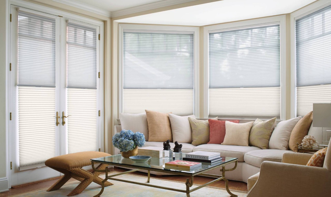 Living room with a large couch and wide windows covered by Hunter Douglas Duette® Cellular Shades near Ann Arbor, MI
